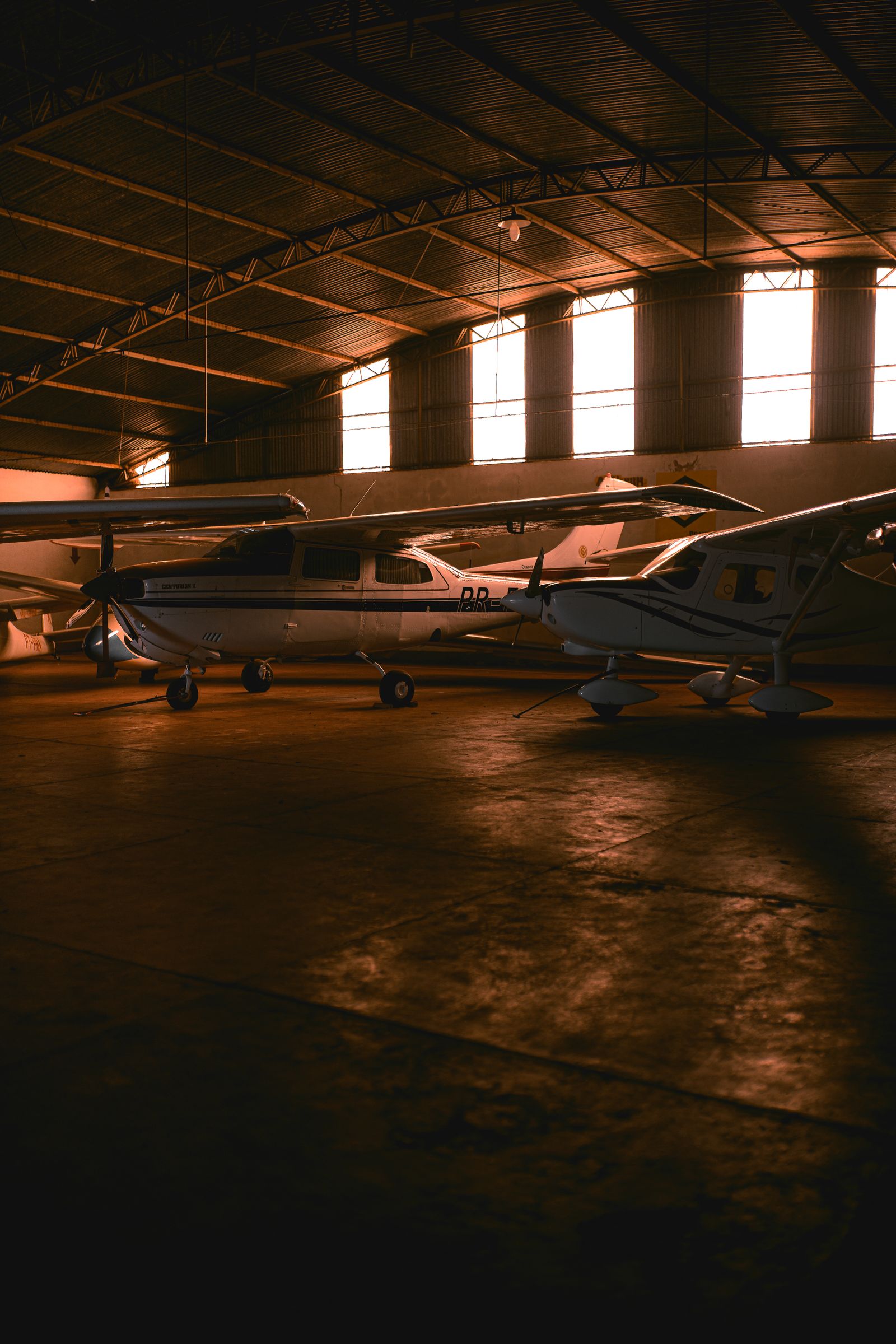 Light aircraft parked inside a bright hangar in daylight