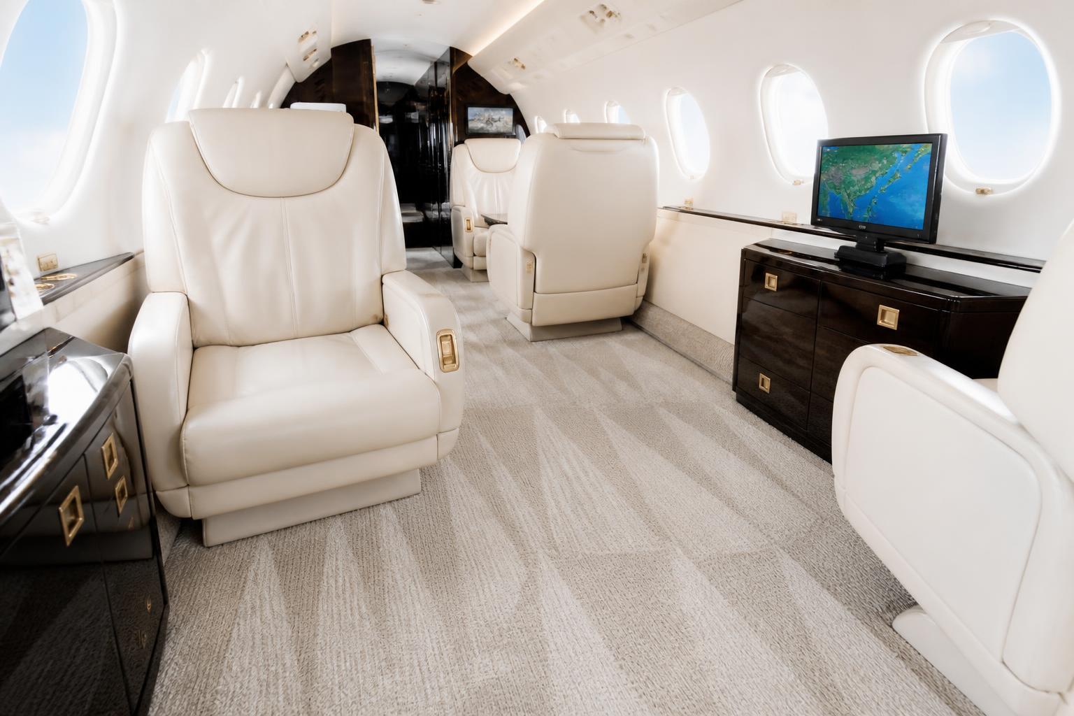 Detailed aircraft cabin with cream leather seats and vacuum lines in the carpet